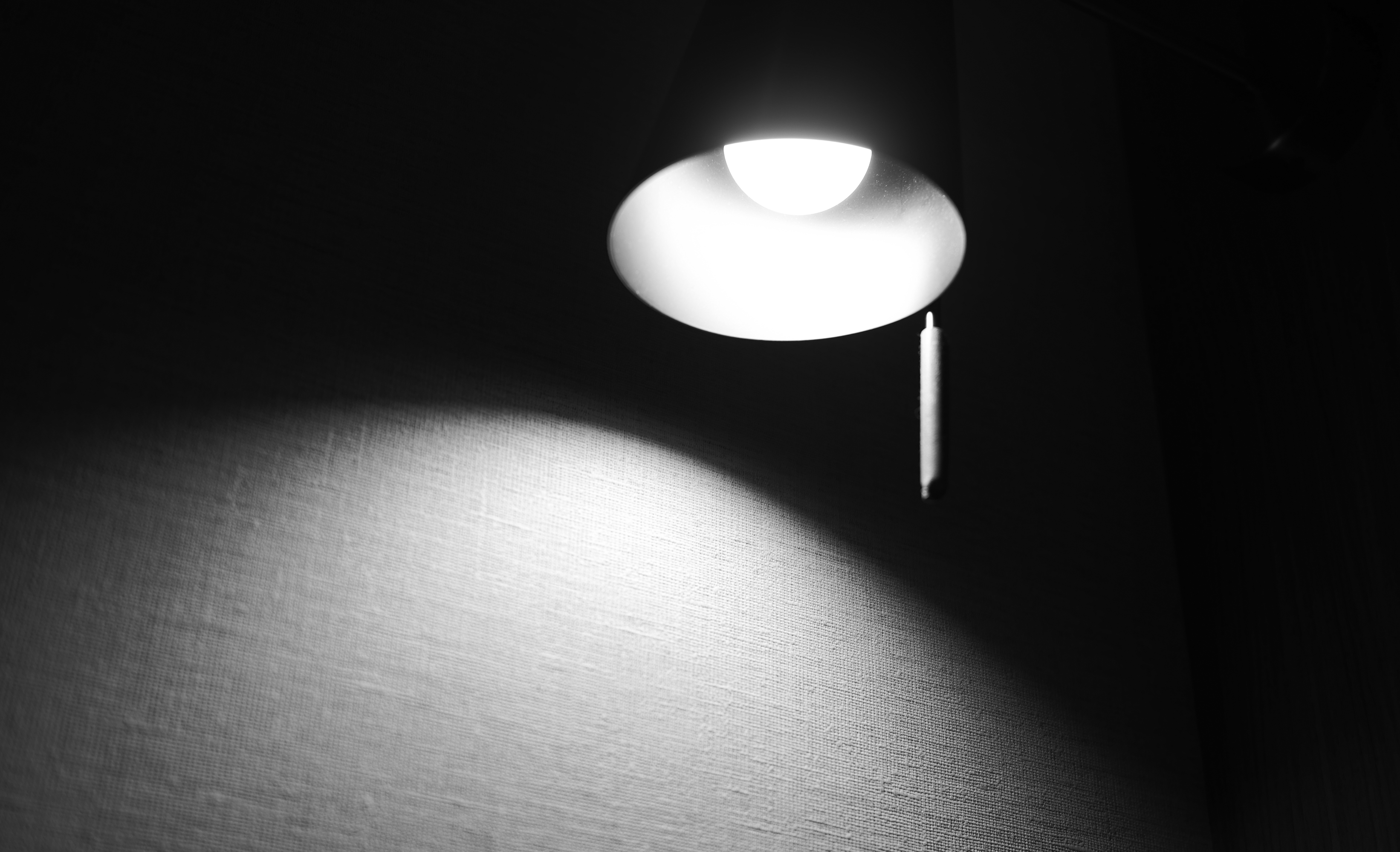 A wall-mounted lamp lighting a textured wall in the dark